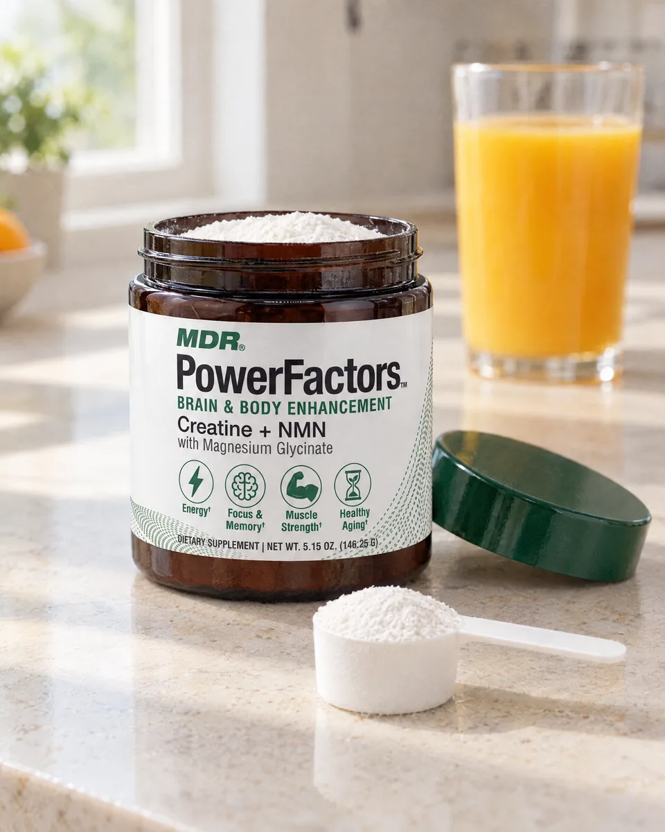 The PowerFactors jar open on a kitchen counter with a scoop of white powder and a glass of orange juice